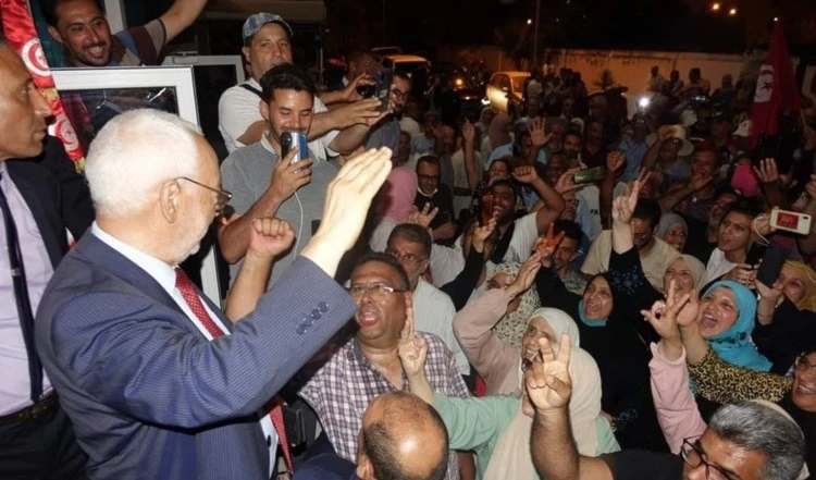 El líder del Movimiento Al-Nahda, Rached  Ghannouchi, saluda a sus seguidores luego de salir del interrogatorio judicial.