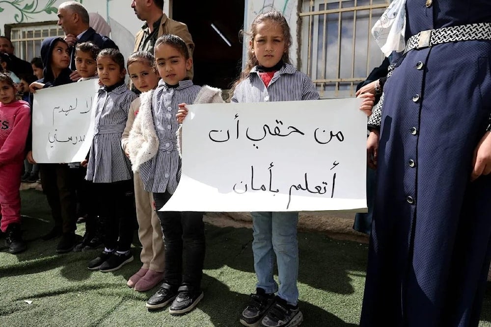 Los pequeños alumnos protestan en las afueras del centro escolar con pancartas donde se puede leer 