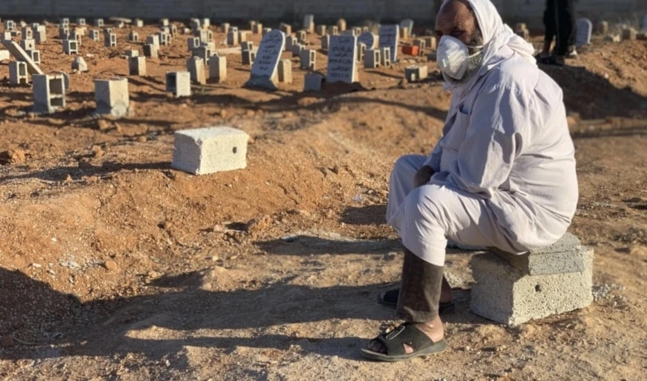 Un hombre sentado junto a las tumbas de las víctimas de las inundaciones repentinas en Derna.