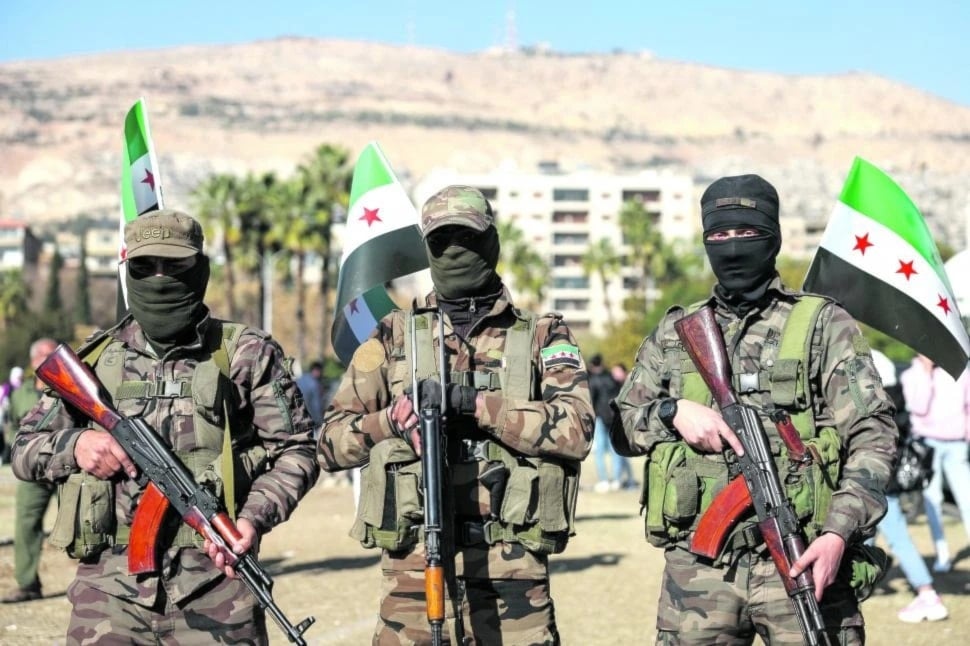 Combatientes del HTS observan una manifestación de estudiantes, cerca del campus de la Universidad de Damasco. (Foto: AFP)