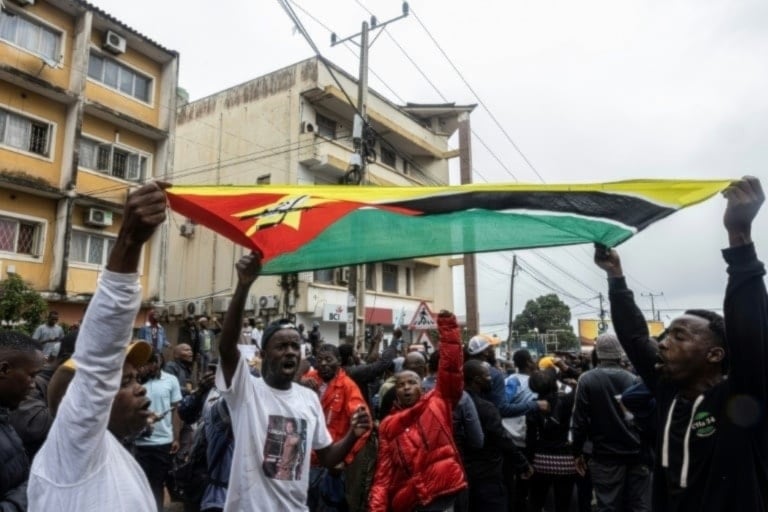 Ciudadanos levantan bandera nacional durante las protestas en Mozambique.