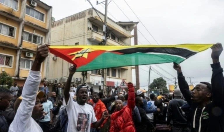 Ciudadanos levantan bandera nacional durante las protestas en Mozambique.