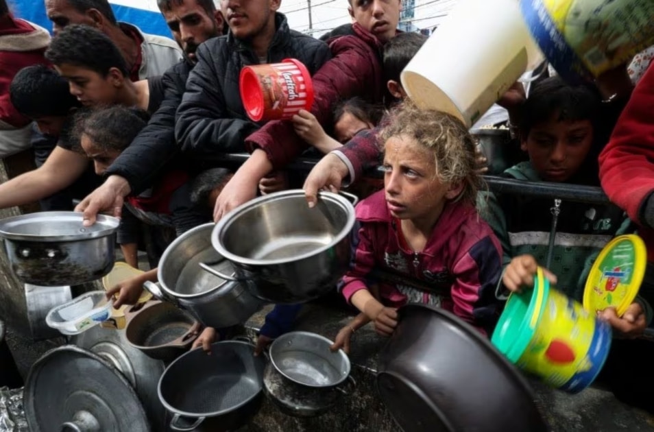 Palestinos con sus niños esperando obtener comida en Rafah.