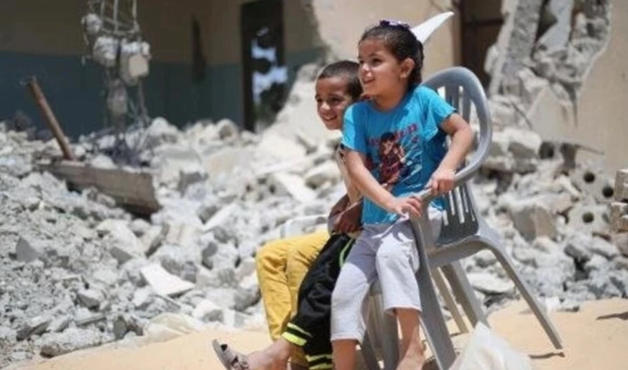 Niños jugando sobre las ruinas de sus casas en la aldea de Al-Khazaa. Foto: Reuters