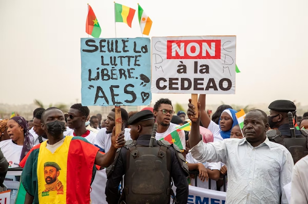 Manifestantes en Bamako portan banderas de Malí, Burkina Faso y Níger durante un acto de apoyo a la decisión de esas tres naciones de retirarse de la CEDAO.