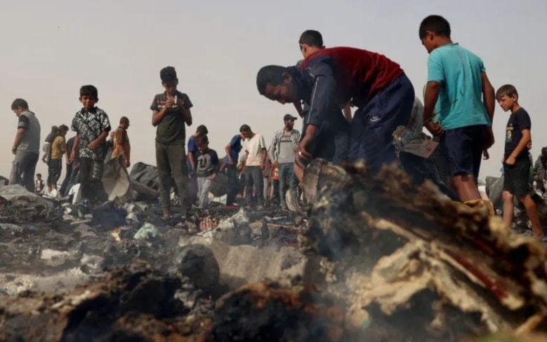 Palestinos frente a tiendas de campaña en llamas después de agresión israelí a Rafah