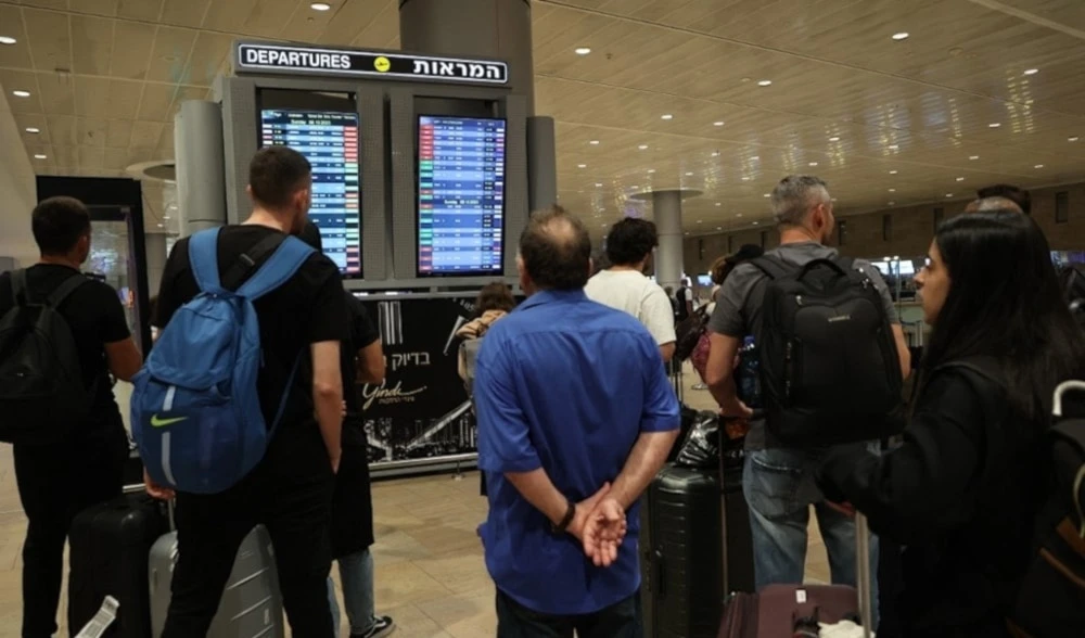 Los pasajeros miran el panel de salidas en el aeropuerto Ben Gurion de "Israel" (AFP)