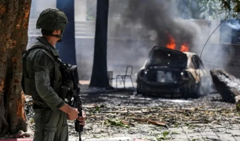 Soldado israelí cerca de coche en llamas debido a ataque con misiles de Hizbullah contra el asentamiento de Kiryat Shemona. Foto: Reuters