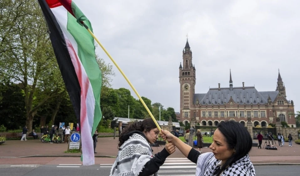 Dos manifestantes izando la bandera de Palestina ocupada frente al Palacio de la Paz, sede de la CIJ, en La Haya. (Foto: AP)