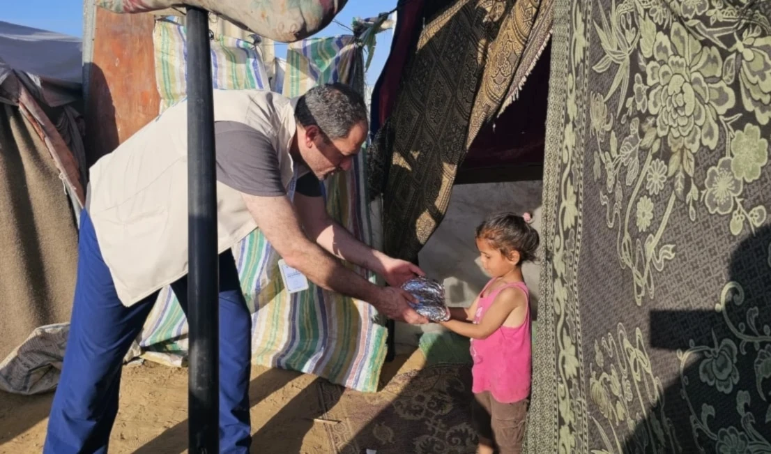 Médico estadounidense de origen palestino distribuye comida a niños en el campamento de refugiados en Khan Yunis, al sur de Gaza. Médico estadounidense de origen palestino distribuye comida a niños en el campamento de refugiados en Khan Yunis, al sur de Gaza.