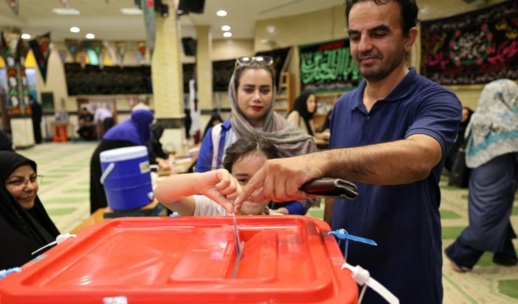 Una niña ayuda a su padre a emitir su voto en un colegio electoral de Teherán, en la segunda vuelta de las elecciones presidenciales iraníes. Foto: AFP