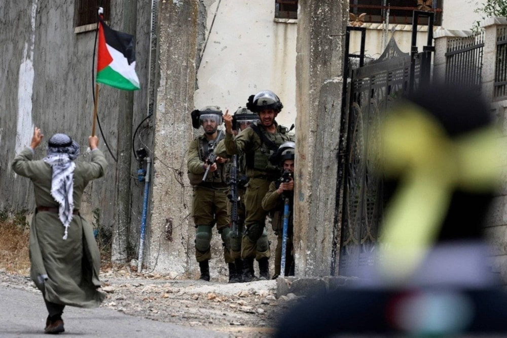 Manifestante ondea la bandera de Palestina frente a las fuerzas de ocupación durante una protesta contra la usurpación de más tierras palestinas en Cisjordania. Foto: AFP