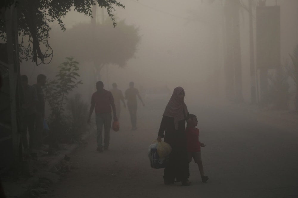 Palestinos caminan entre polvo y humo después del ataque israelí a un edificio en el campamento de refugiados de Nuseirat, en el centro de la Franja de Gaza. (Foto: AFP)