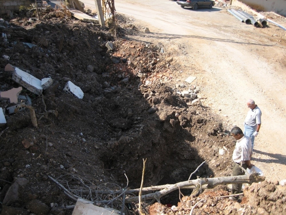 El Dr. Ali Khobeisi (derecha) tomando lecturas del contador Geiger en un cráter de bomba en Khiam, Líbano, 2006.