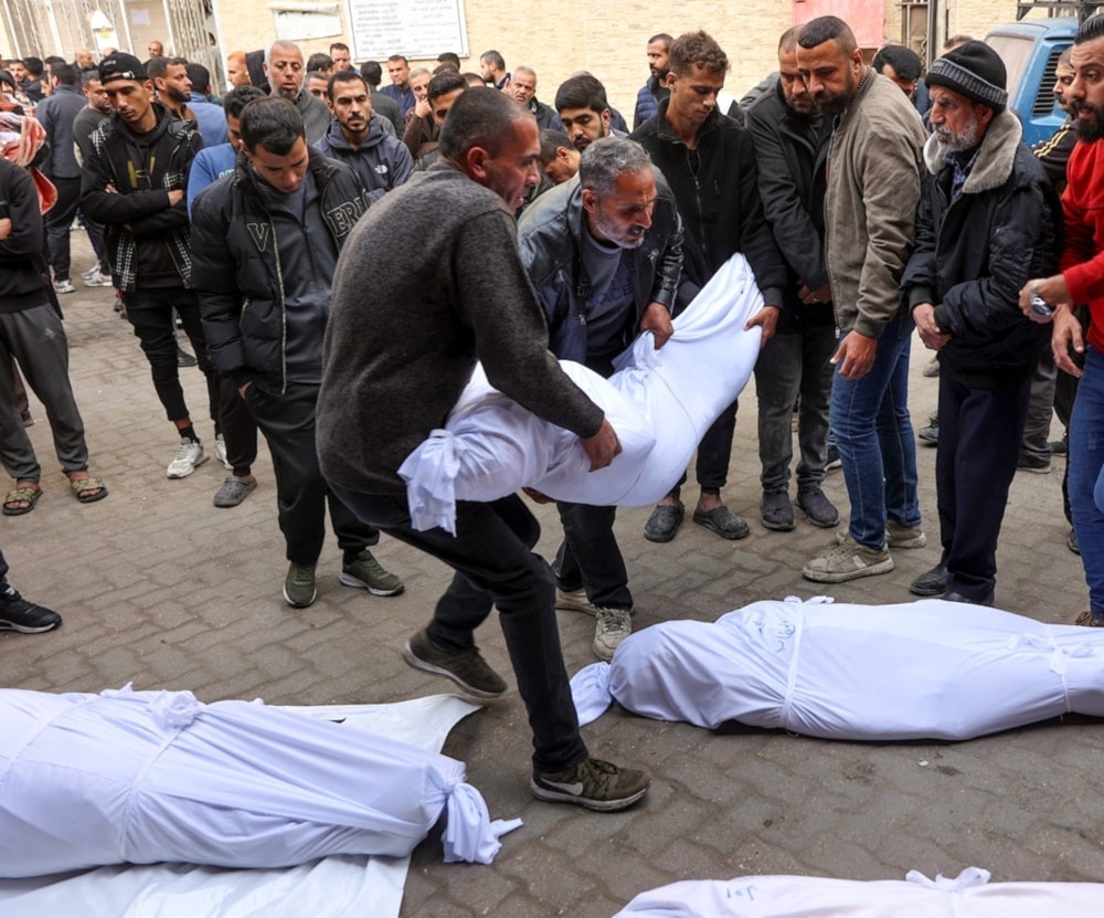 Palestinos cargan los cuerpos amortajados de los mártires en el hospital Al-Ahli. 