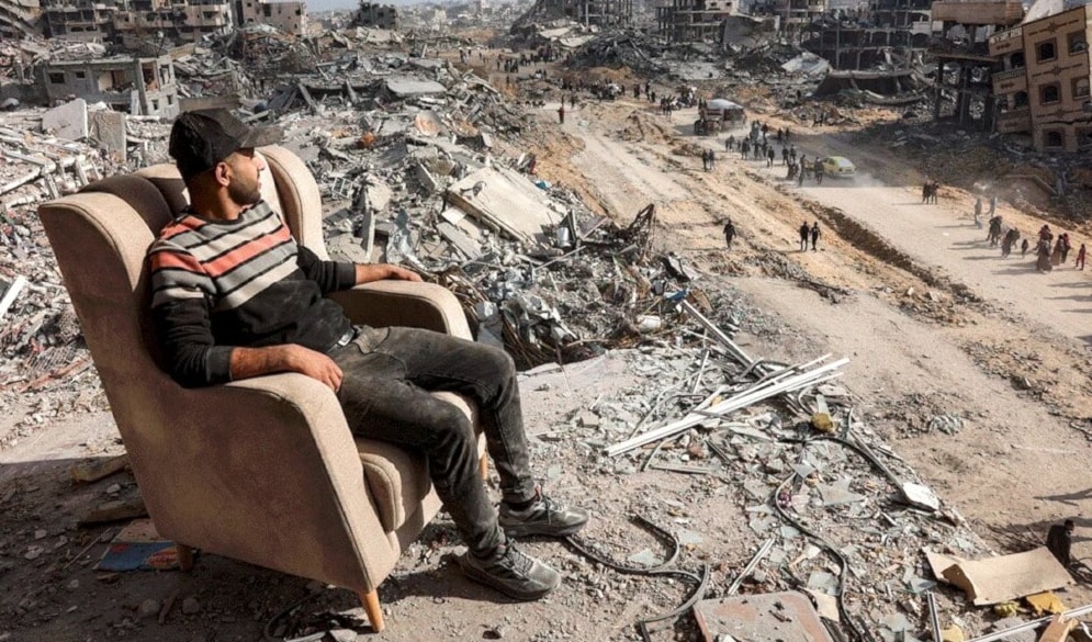 Palestino sentado de un silla entre los escombros de un edificio destruido en la calle Al-Saftawi, norte de Gaza. 20 de enero de 2025 (Foto: AFP)