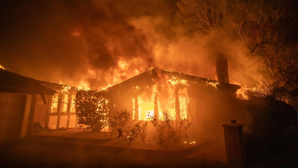 Llamas del incendio de Palisades queman una casa durante una poderosa tormenta de viento.