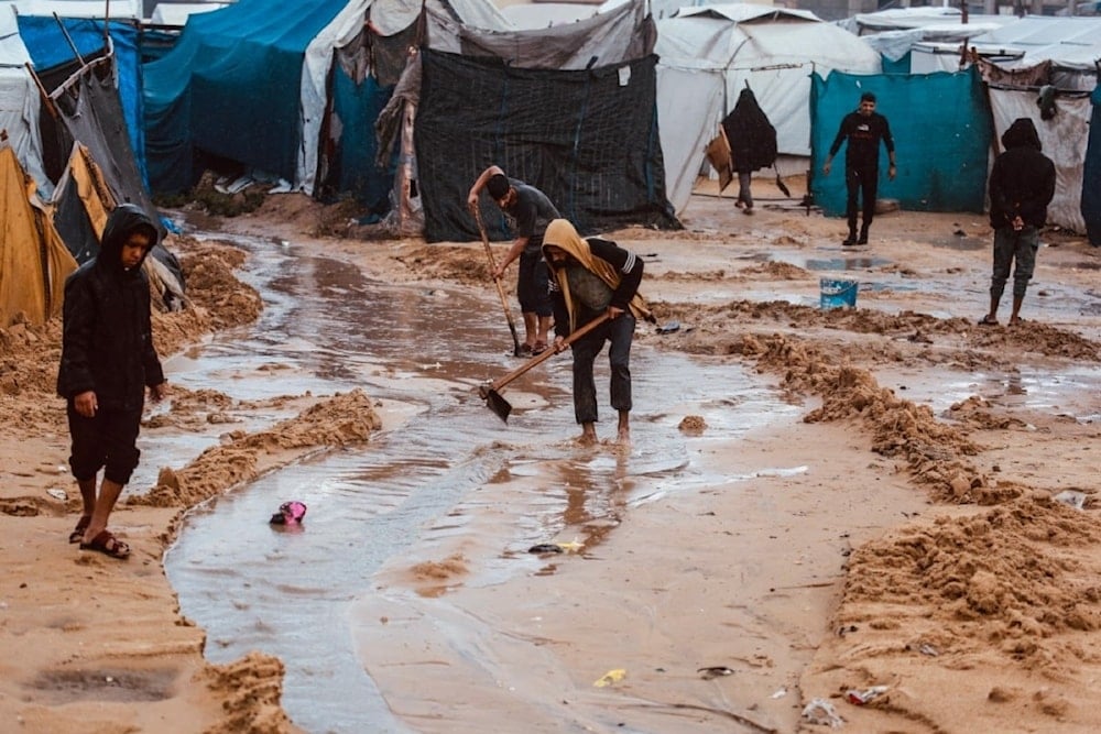 Palestinos cavan canales en la arena para desviar el agua de lluvia en Deir al-Balah. 25 de noviembre de 2025