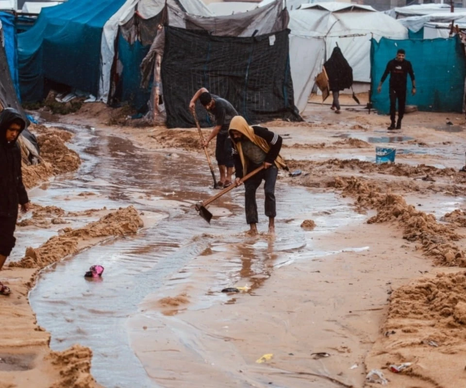 Palestinos cavan canales en la arena para desviar el agua de lluvia en Deir al-Balah. 25 de noviembre de 2025