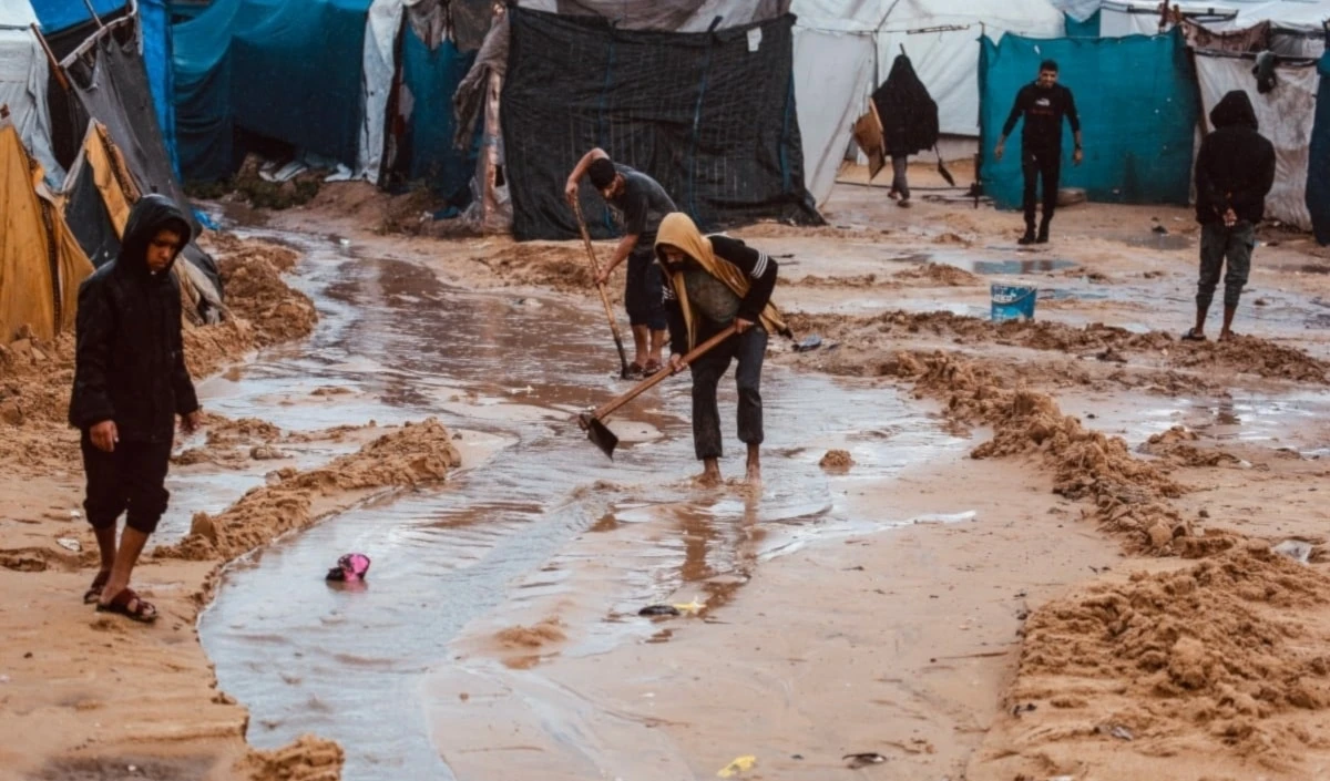 Palestinos cavan canales en la arena para desviar el agua de lluvia en Deir al-Balah. 25 de noviembre de 2025