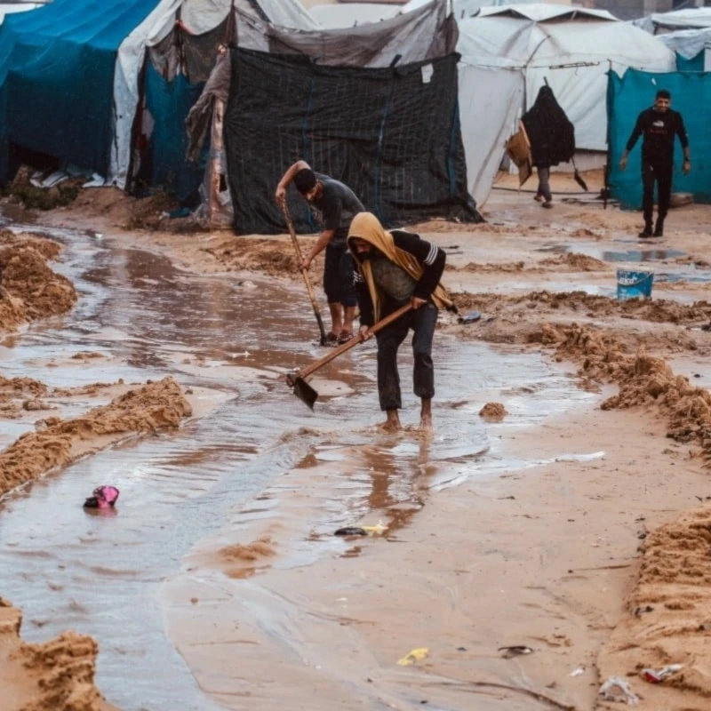 Palestinos cavan canales en la arena para desviar el agua de lluvia en Deir al-Balah. 25 de noviembre de 2025