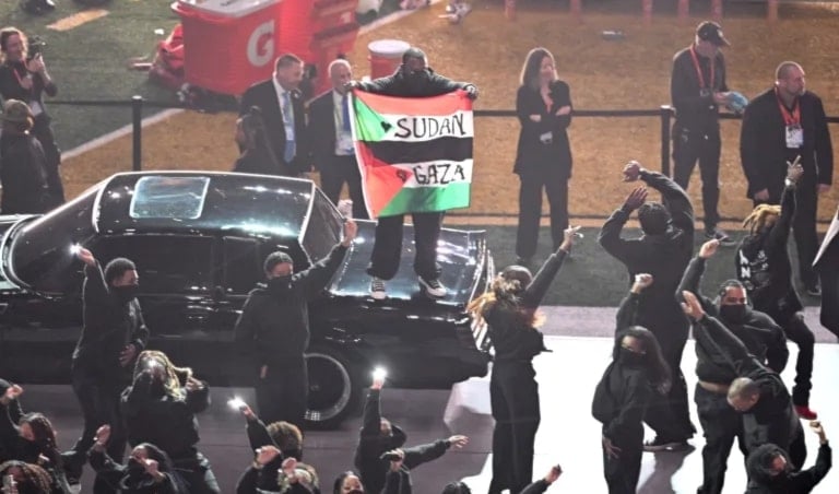 El manifestante sostenía una bandera palestina con las palabras “Gaza” y “Sudán” escritas sobre ella. 