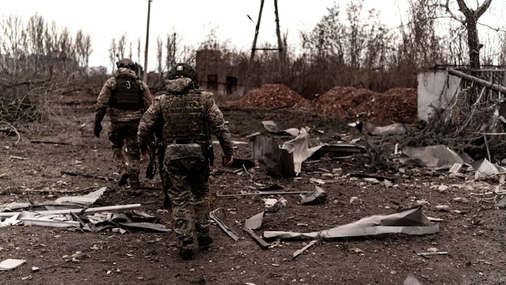 Soldados caminan entre escombros mientras civiles evacuan Pokrovsk, en el este de Ucrania.