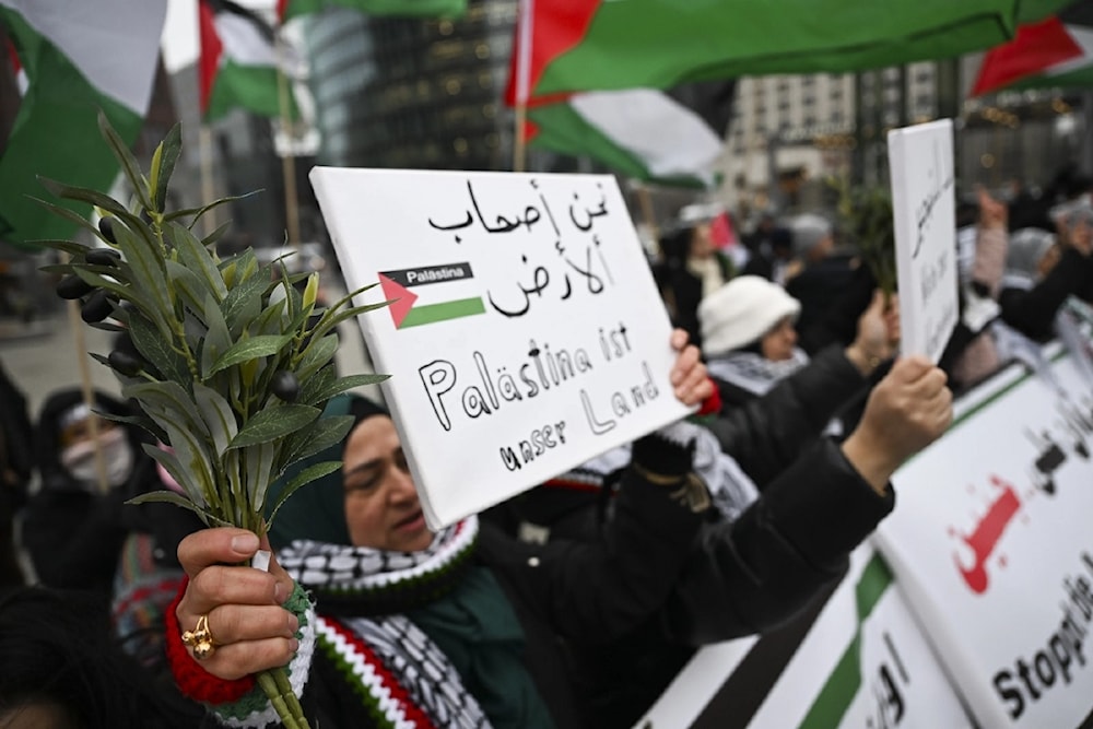 Somos los dueños de la tierra, señala un cartel en manos de una mujer palestina.