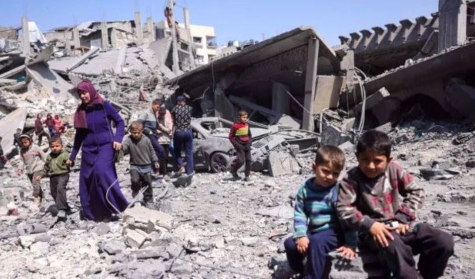 Niños observan a la gente caminar entre los escombros de un edificio destruido en un ataque israelí en Jabalia, en el norte de la Franja de Gaza, el 18 de marzo de 2025. Foto: AFP