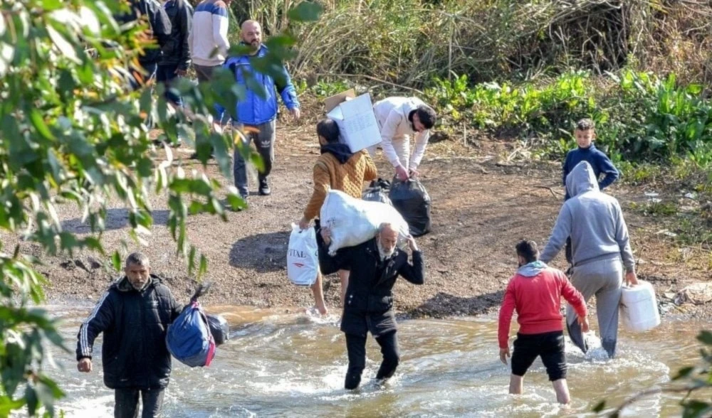 Sirios de la minoría alawita cruzan el Gran Río que forma la frontera entre la provincia costera occidental de Siria y el norte del Líbano, en Hakr al-Dahr.