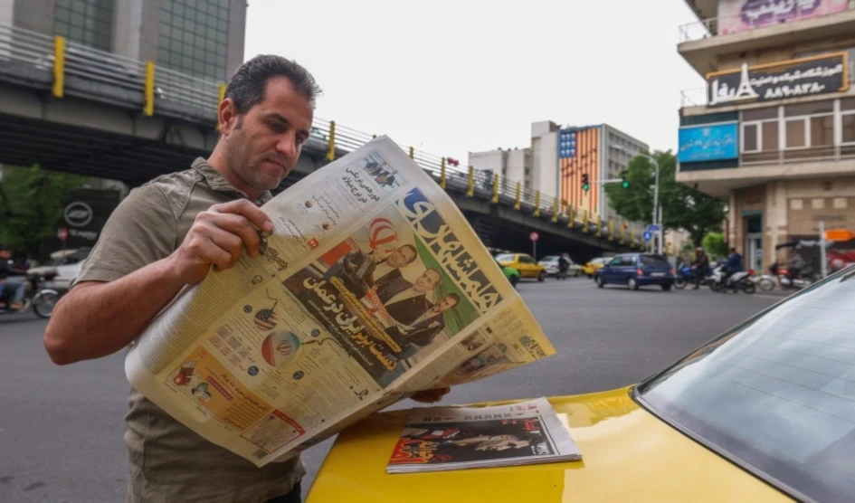 Un iraní lee un periódico en una calle de Teherán el 12 de abril de 2025. La portada presenta las conversaciones indirectas entre Irán y Estados Unidos en Omán ese mismo día. Foto: AFP