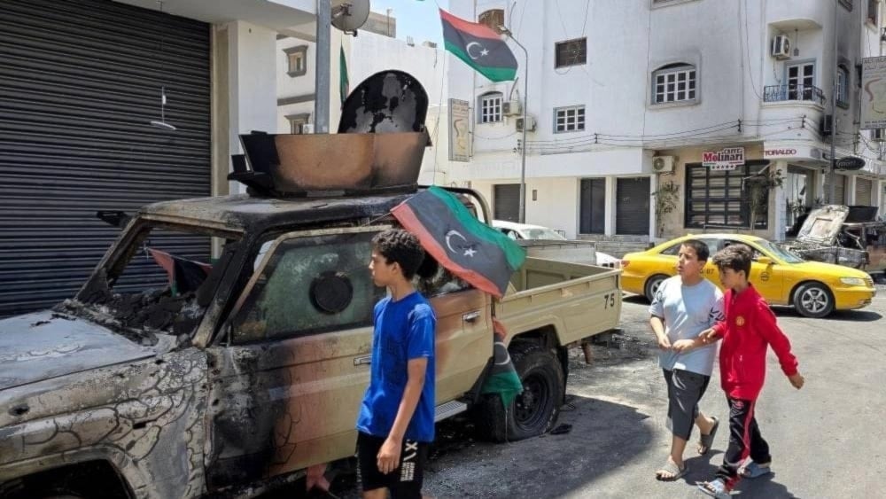 Niños pasan junto a un coche destruido durante los enfrentamientos armados.