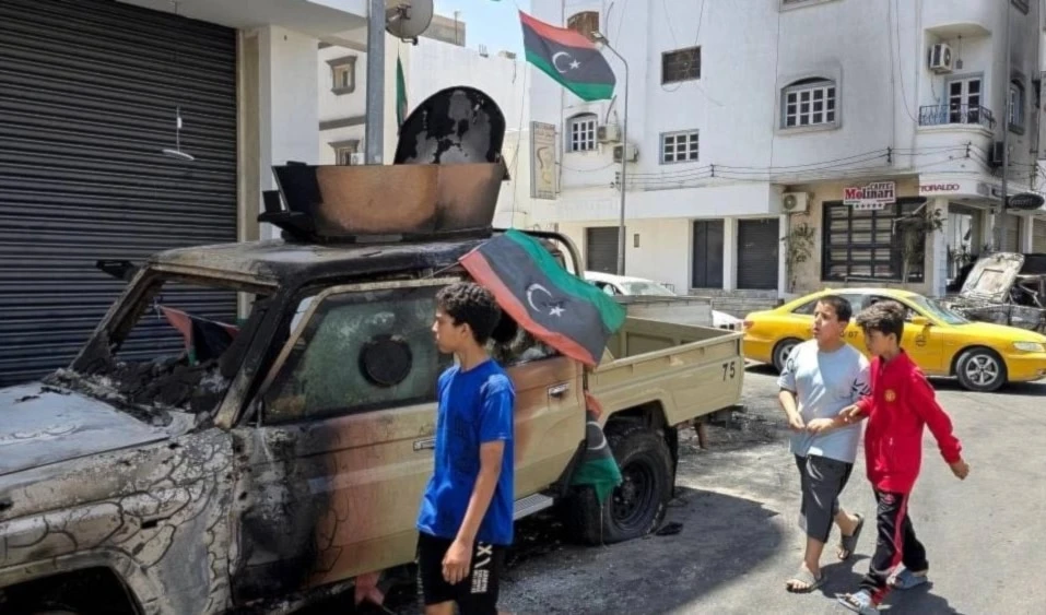 Niños pasan junto a un coche destruido durante los enfrentamientos armados.