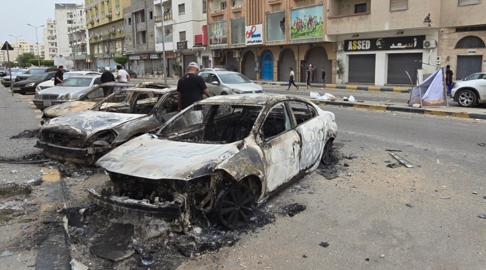 Coches incendiados bordean una calle de Trípoli el 14 de mayo de 2025, tras los renovados enfrentamientos en la capital de Libia. Foto: AFP