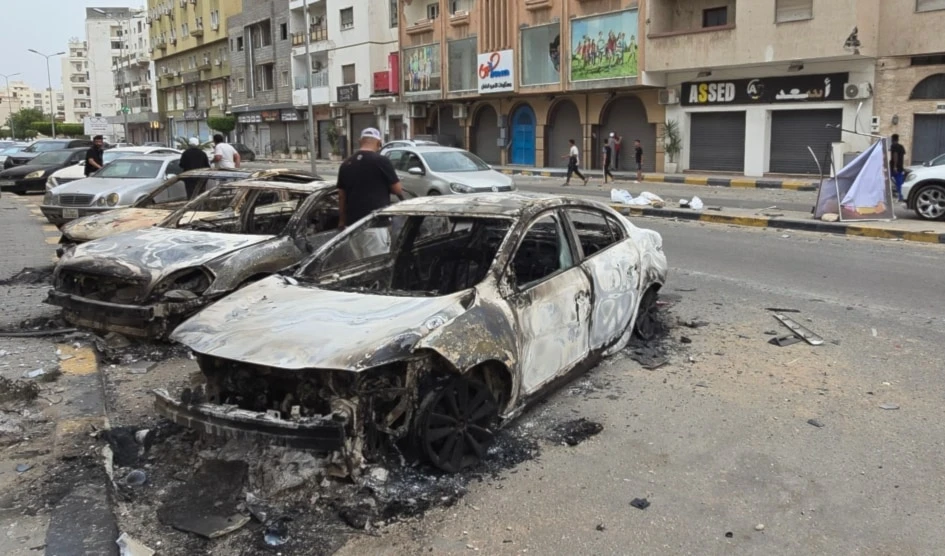Coches incendiados bordean una calle de Trípoli el 14 de mayo de 2025, tras los renovados enfrentamientos en la capital de Libia. Foto: AFP