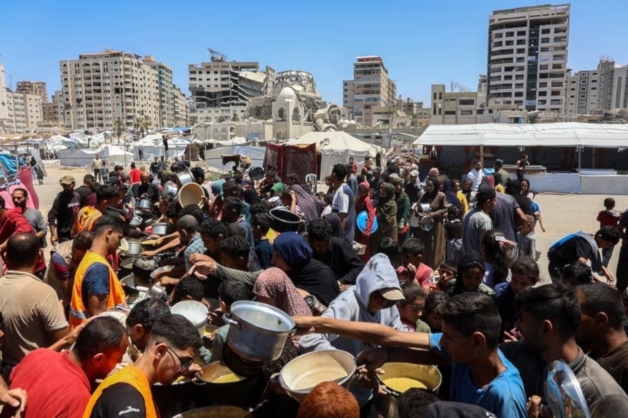 Palestinos esperan comidas en un punto de distribución de alimentos en la ciudad de Gaza. 21 de mayo de 2025. (Foto: AFP)