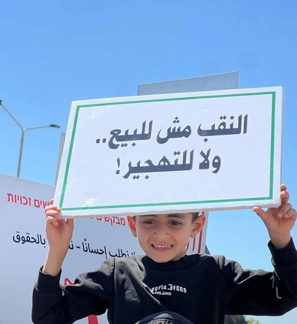 Niño palestino sostiene un cartel que dice: El Negev no está en venta.