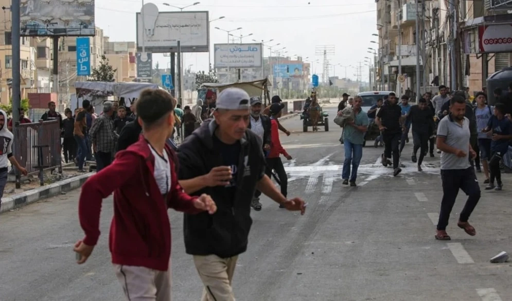 Palestinos se alejan de un punto de distribución de ayuda cerca del puesto de control de Netzarim, en el centro de la Franja de Gaza.
