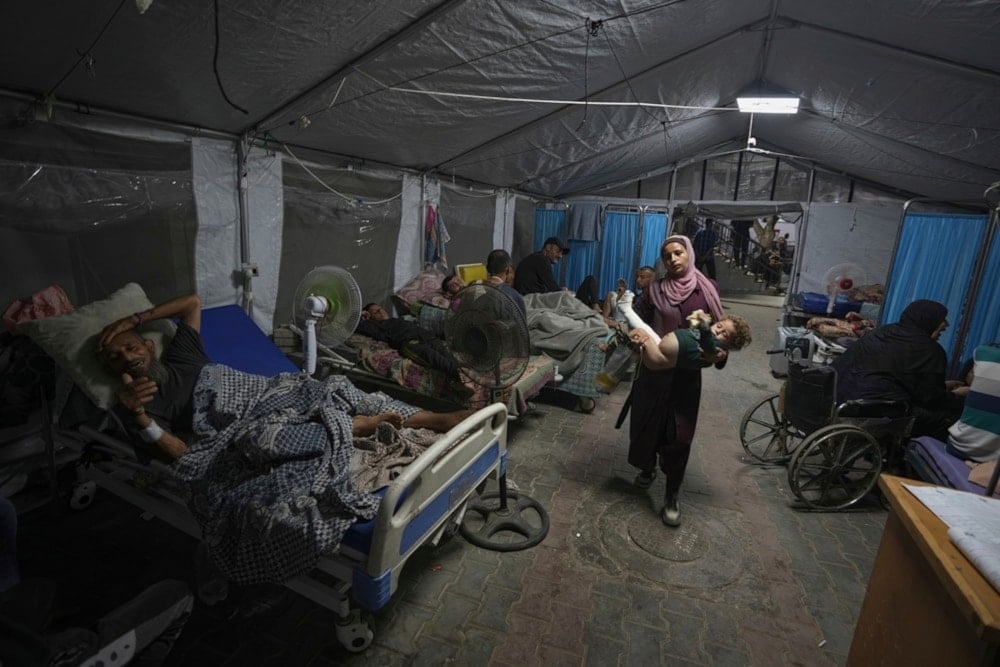 Madre palestina sostiene a su hijo en brazos a una tienda de campaña instalada en el patio del hospital Al-Shifa. 4 de julio de 2025 (Foto: AP)