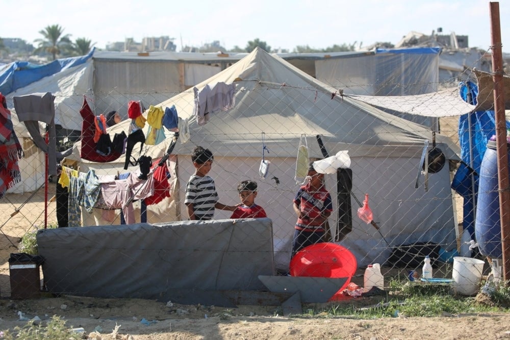 Niños junto a tiendas de campaña en un campamento para palestinos desplazados en el centro de la Franja de Gaza. 7 de julio de 2025 (Foto: AFP)
