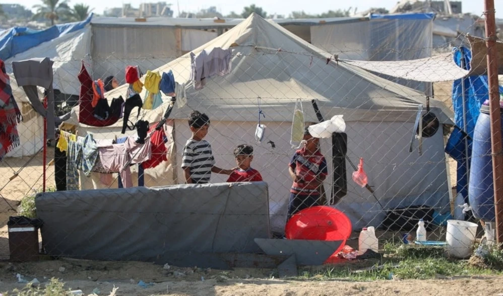 Niños junto a tiendas de campaña en un campamento para palestinos desplazados en el centro de la Franja de Gaza. 7 de julio de 2025 (Foto: AFP)