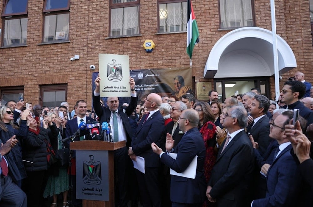 El embajador Husam Zomlot sostiene un cartel con la frase “Embajada del Estado de Palestina” durante el izado de la bandera frente diplomática en Londres. (Foto: AFP)