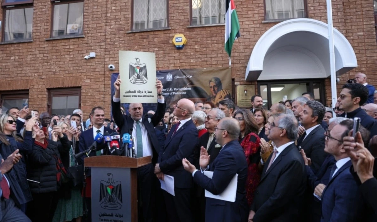 El embajador Husam Zomlot sostiene un cartel con la frase “Embajada del Estado de Palestina” durante el izado de la bandera frente diplomática en Londres. (Foto: AFP)