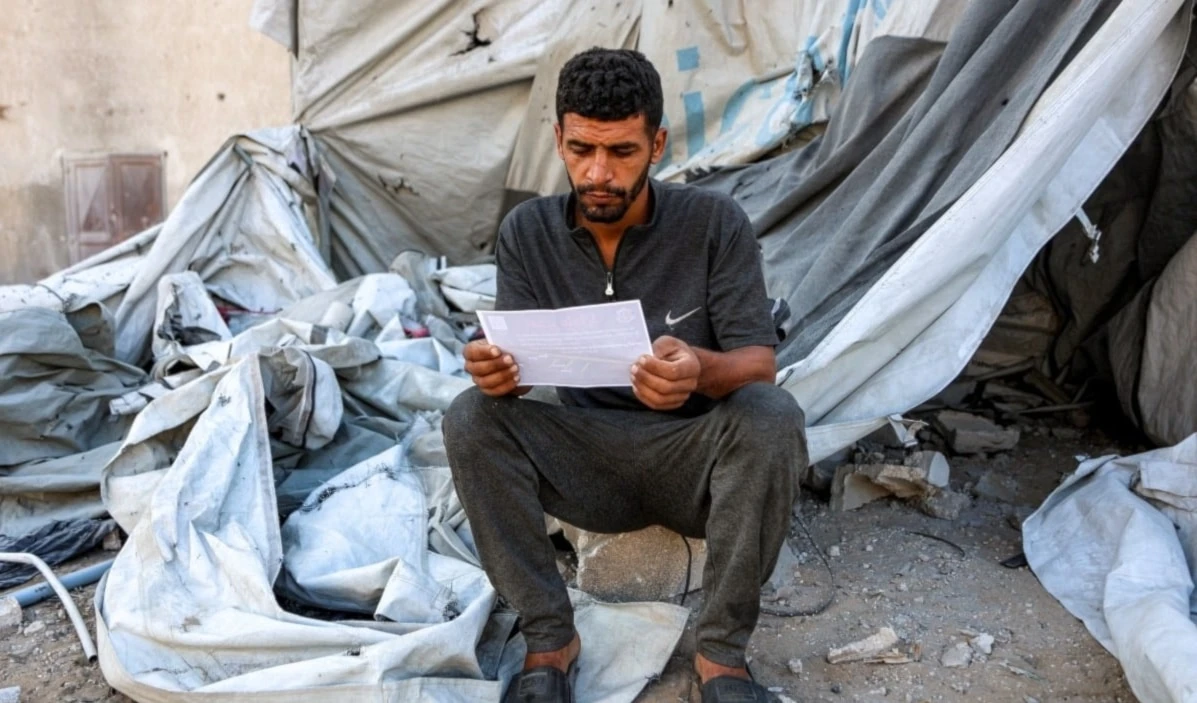 Palestino lee folleto lanzado por las fuerzas de ocupación israelíes sobre la ciudad de Gaza para instarlo evacuar del sur hacia Al-Mawasi.